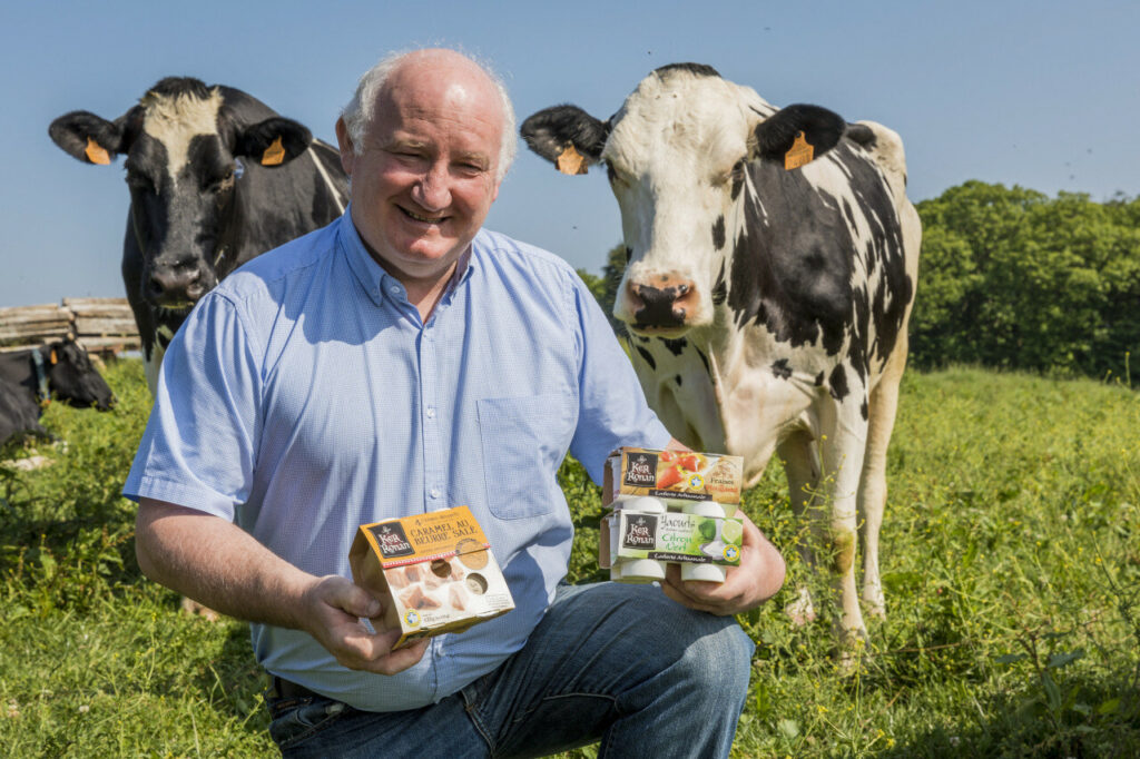 Nous voyons deux vaches dans le fond avec un monsieur qui présente ses produits les yaourts de Ker Ronan